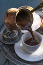 Roasted Turkish coffee. Pouring of hot coffee from cezve into cup on table Royalty Free Stock Photo