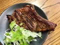 Roasted Veal Chop with Salad in Black Plate at Restaurant