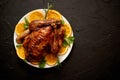 Roasted whole chicken or turkey served in white ceramic plate with oranges