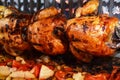 Roasted whole chickens rolling over roasted vegetables in a grilling box with refraction. Royalty Free Stock Photo