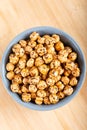 Roasted, yellow chickpeas in ceramic bowl on wooden
