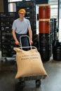 Roastery worker standing with sacks with coffee beans uploading. Royalty Free Stock Photo