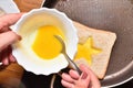 Roasting bread toasts with a star-shaped middle and a girl`s hand fills it with a beaten egg to create a sandwich. Bread is fried