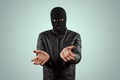Robber, bandit in a balaclava surrenders on a light background. Robbery, hacker, crime, theft. Copy space