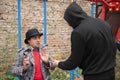 A robber in black clothes threatens a man with a knife on a city street Royalty Free Stock Photo