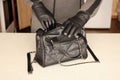 Robber in black outfit and gloves see on opened stolen women bag. A thief evaluates the value of stolen items from a womans Royalty Free Stock Photo