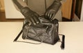 Robber in black outfit and gloves see on opened stolen women bag. A thief evaluates the value of stolen items from a Royalty Free Stock Photo