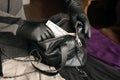 Robber in black outfit and gloves see in opened stolen women bag. The thief takes out US dollar bills from a womans handbag in Royalty Free Stock Photo