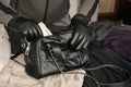 Robber in black outfit and gloves see in opened stolen women bag. The thief takes out US dollar bills from a womans handbag in Royalty Free Stock Photo