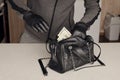 Robber in black outfit and gloves see in opened stolen women bag. The thief takes out US dollar bills from a womans handbag in Royalty Free Stock Photo