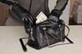 Robber in black outfit and gloves see in opened stolen women bag. The thief takes out US dollar bills from a womans handbag in Royalty Free Stock Photo