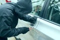 Robber man in black hoodie jacket using a screwdriver  to break lock and steal a vehicle. Car thief or theft for insurance concept Royalty Free Stock Photo