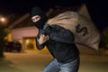 Robber runs away and is carrying full bag of money at night. Royalty Free Stock Photo