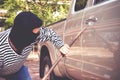 The robber wearing a black mask holds an iron bar to destroy the car door. Royalty Free Stock Photo