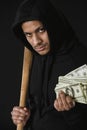 Robber in zoodie with baseball bat and money isolated on black