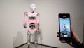 Robot Captured Through Smartphone Lens in Modern Exhibit. A humanoid robot is viewed through a smartphone screen as it