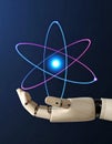 Robot hand holding a glowing blue and pink atom model against a dark background Royalty Free Stock Photo