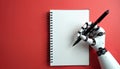 Robot hand holds pen over blank notebook on red background. Automation creates ideas and writes text for future projects. Tech, Royalty Free Stock Photo