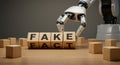 Robot hand interacting with blocks spelling fake and fact: concept of misinformation and ai influence Royalty Free Stock Photo