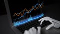 Robot hand interacting with laptop displaying financial data on dark background, symbolizing artificial intelligence in Royalty Free Stock Photo