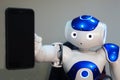 The robot holds the phone in his hand . A small robot with a human face and a humanoid body. Artificial intelligence-AI.