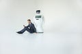 Businessman uses a smartphone while sitting on the floor next to a robot. Modern Robotic Technologies. Humanoid