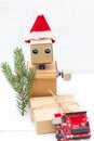 A robot in a santa hat holds a branch of a Christmas tree and a