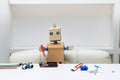 robot sits at a table and holds a screwdriver lying next to a robot parts for assembly