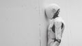 A robot standing against a wall with its head turned to the side, AI