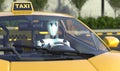Robot taxi driver sits at the wheel of a yellow taxi. Car with autopilot. Future concept with smart robotics and artificial