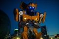 Robot transformer Bumblebee stands in street and glows in dark against night city Royalty Free Stock Photo