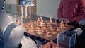 A robotic arm and a little girl are rearranging chess pieces