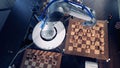 A robotic arm is moving chess pieces being surrounded by three chessboards