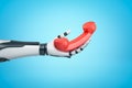 Robotic hand holding red retro telephone receiver on blue background Royalty Free Stock Photo