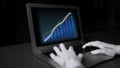 Robotic Hand Interacting with Laptop Screen Displaying Financial Growth Graphs and Data Analysis in Dark Room Setting Royalty Free Stock Photo