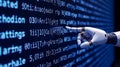 A robotic hand points at a screen displaying complex digital code Royalty Free Stock Photo