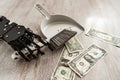 Robotic hand wielding a dustpan and brush, meticulously sweeping up one-dollar bills Royalty Free Stock Photo