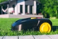 Robotic Lawn Mower cutting grass in the garden. Automatic robot lawnmower in modern garden on sunny day Royalty Free Stock Photo