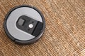 Robotic vacuum cleaner on brown rug, above view. Space for text