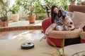 Robotic vacuum cleaner on carpet, woman in blue shirt plays with dog, Jack Russell Terrier breed at home on couch, , enjoying life Royalty Free Stock Photo