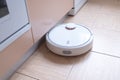 Robotic vacuum cleaner on the floor cleaning the kitchen. Smart cleaning technology. Royalty Free Stock Photo