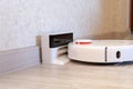 Robotic vacuum cleaner on laminate wood floor charging from base station