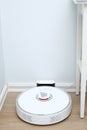 Robotic vacuum cleaner on laminate wood floor charging from base station. Smart cleaning technology. robot vacuum cleaner return Royalty Free Stock Photo