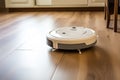 Robotic vacuum cleaner on laminate wood floor. Modern smart cleaning technology