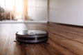 Robotic vacuum cleaner on laminate wood floor smart cleaning technology. Selective focus. Royalty Free Stock Photo