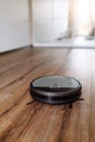 Robotic vacuum cleaner on laminate wood floor smart cleaning technology. Selective focus. Royalty Free Stock Photo