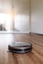 Robotic vacuum cleaner on laminate wood floor smart cleaning technology. Selective focus. Royalty Free Stock Photo