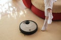 Robotic vacuum cleaner and legs on carpet, smart appliances in the home concept, lazy and comfort lifestyle