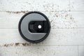 Robotic vacuum cleaner removing scattered buckwheat from wooden floor, top view