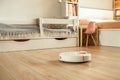 Robotic vacuum cleaner working on laminate wood floor in the living room. Automated white vacuum cleaner robot in the Scandinavian Royalty Free Stock Photo